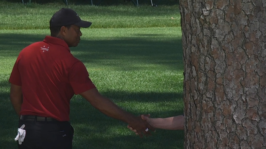 Tiger shakes hands with Verne Lundquist during round
