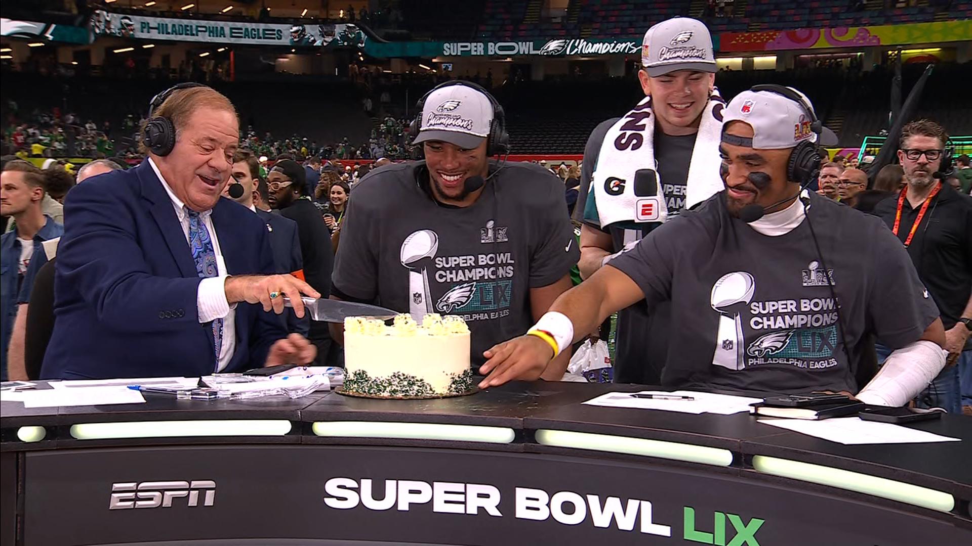 Chris Berman delivers a birthday cake to Saquon Barkley and Cooper DeJean